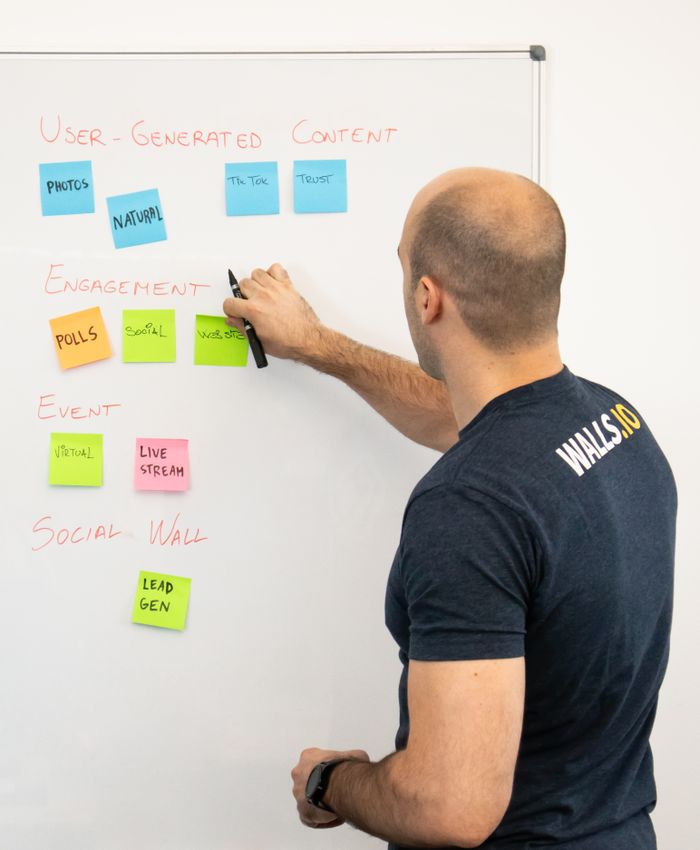Un homme analyse des stratégies de contenu marketing à l'aide de notes adhésives sur un tableau blanc.